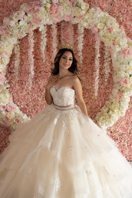 Quinceañera elegante with Quinceañera dresses, a woman in a Quinceañera dress standing in front of a flower wall
