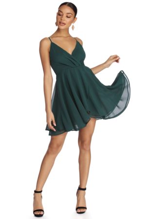 A woman in a green surprise dance dress poses for a picture at a Quinceanera