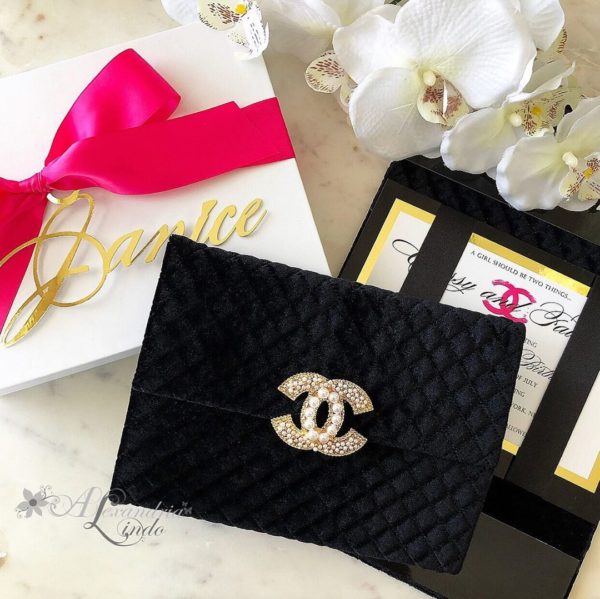 Quinceanera handbag, a black purse with a gold logo and a pink bow