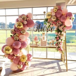 Quinceanera decoration with a balloon arch decorated with pink and gold balloons and vintage balloon decor.