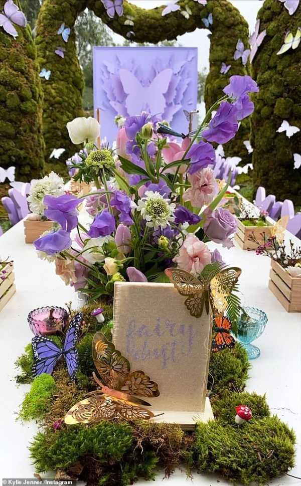 A Quinceanera-themed image featuring a table topped with a vase filled with purple flowers for a Kylie Jenner butterfly party.