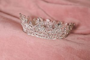 A silver crown headpiece on a pink cloth, perfect for a Quinceanera event