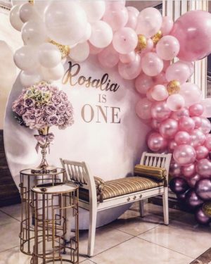 Quinceañera balloon backdrop in a room with a bunch of balloons and a bench