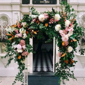 A Quinceanera arch with a fresh flower backdrop and floral design, decorated with flowers and greenery