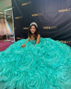 A young girl in a turquoise gown Quinceañera dress posing for a picture