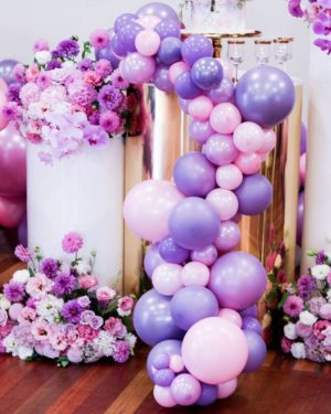 Quinceanera: Pink and purple balloon garland with a bunch of purple and white balloons and flowers