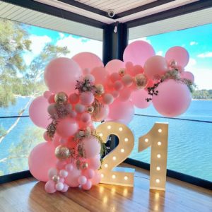 Quinceanera celebration with birthday balloons decoration, featuring a balloon arch with the number 21 and colorful balloons