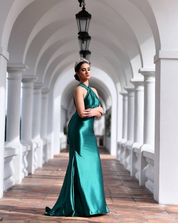 Quinceanera: A woman in a green dress posing for a picture, wearing a gown