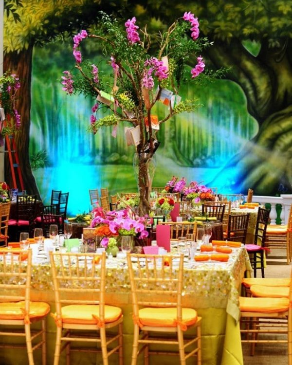A Quinceanera function hall with a floral design, featuring a table set up for a Quinceanera party. The table is adorned with a beautiful tree centerpiece.