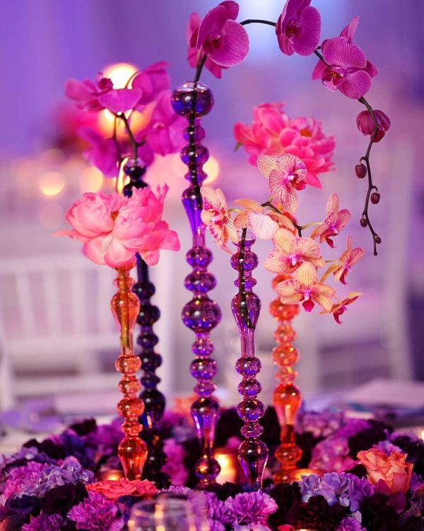 A quinceanera-themed image featuring a floral design, with a vase filled with flowers and candles on a table.