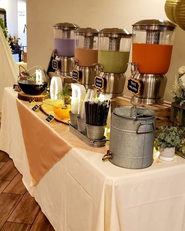 A table with a bunch of drinks on it serving a Quinceanera meal.
