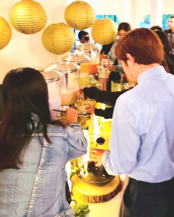 Quinceanera celebration with a table filled with bubble tea drinks and a group of people standing around