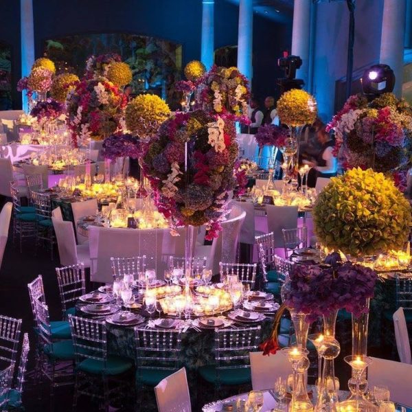 Floral design in a Quinceanera function hall with lots of tables and chairs