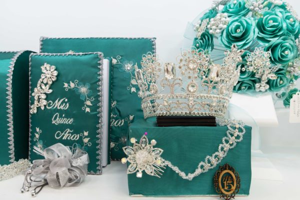 A table with a turquoise Quinceañera theme, displaying a variety of items.