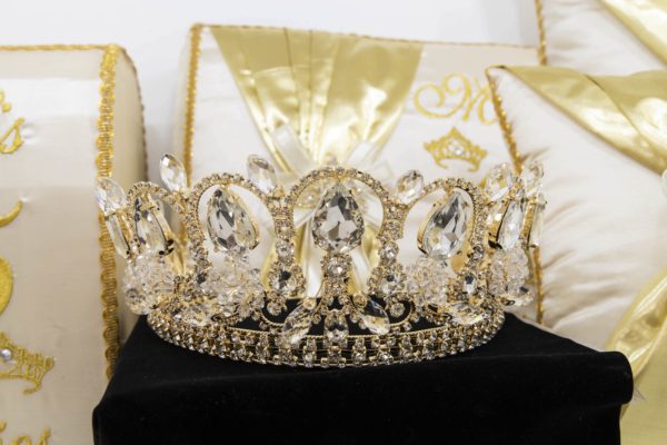 A gold crown sitting on top of a pillow, representing Quinceañera jewellery