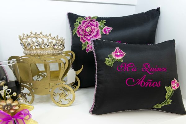 Quinceanera-inspired throw pillow, featuring a couple of pillows sitting on top of a table