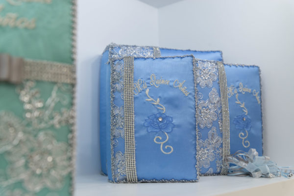 A patchwork Quinceañera with a blue purse sitting on top of a white shelf