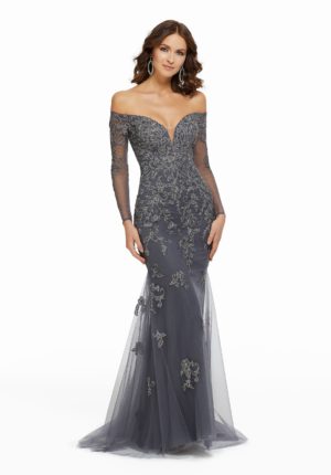 A woman wearing a grey dress with sheer sleeves, perfect for a Quinceanera celebration. Mom dresses for Quinceanera