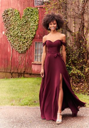 Morilee 21528 - A woman standing in front of a red barn, representing a Quinceanera theme.