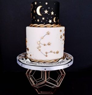 A Quinceanera cake, featuring a black and white design with gold stars