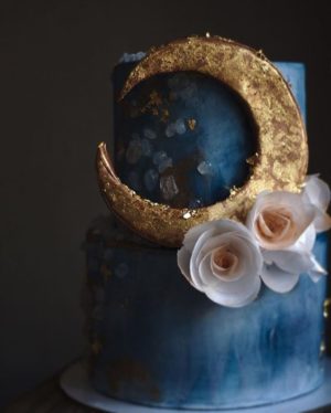 A Quinceanera image featuring decorations, quince cards, moon and stars, and a blue and gold cake with a crescent on top.