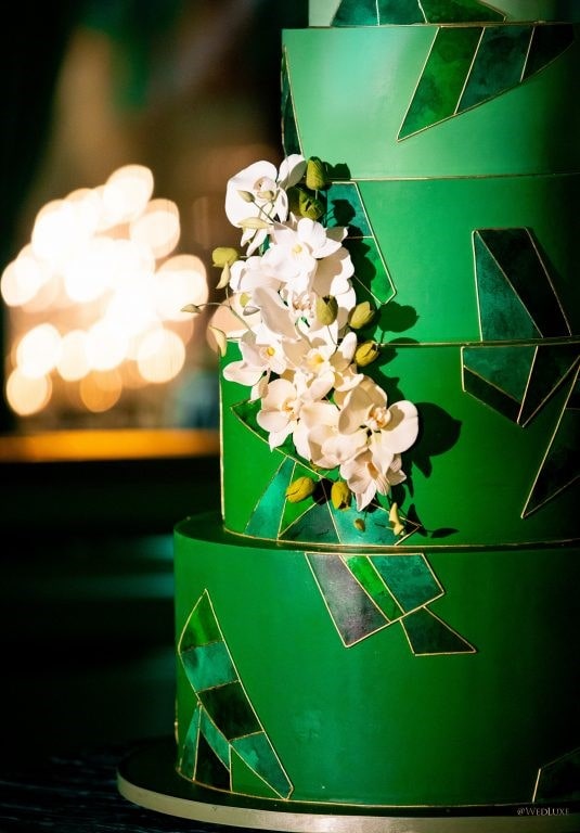 A close up of a green Quinceanera cake with white flowers