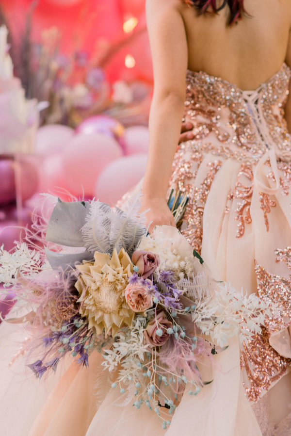 A woman in a Quinceanera gown holding a bouquet, featuring beautiful lace accents