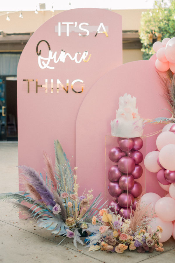 Floral design, a pink arch with balloons and a cake for Quinceanera celebration