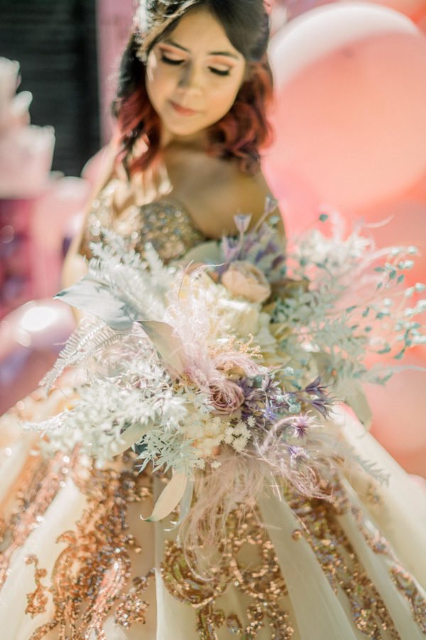 A woman in a Quinceanera dress holding a bouquet of flowers