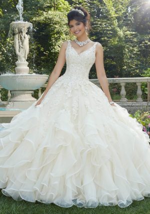 A woman in a wedding dress standing in front of a fountain, wearing lace quinceanera dresses