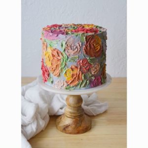A Quinceanera flowerpot party featuring a multicolored cake on a wooden stand.