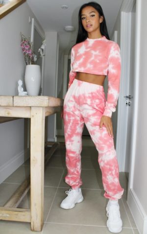 A woman wearing a pink tie dye tracksuit consisting of a top and pants