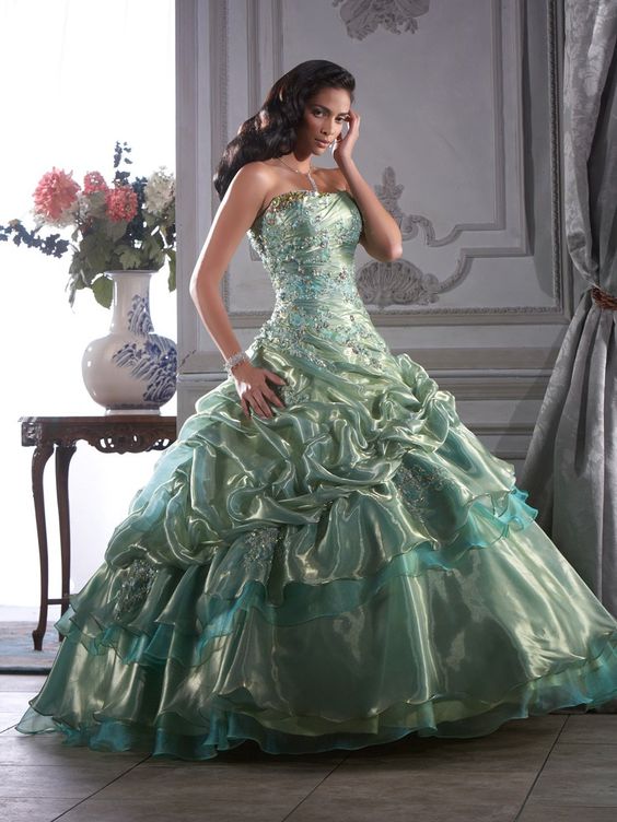 A woman in a green dress posing for a picture, wearing a Quinceanera dress in the color green-gray
