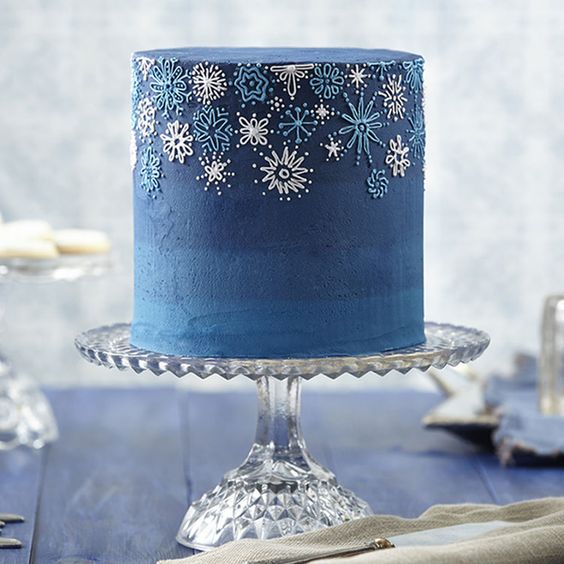 A beautiful winter Quinceanera cake, a blue frosted cake sitting on top of a table.