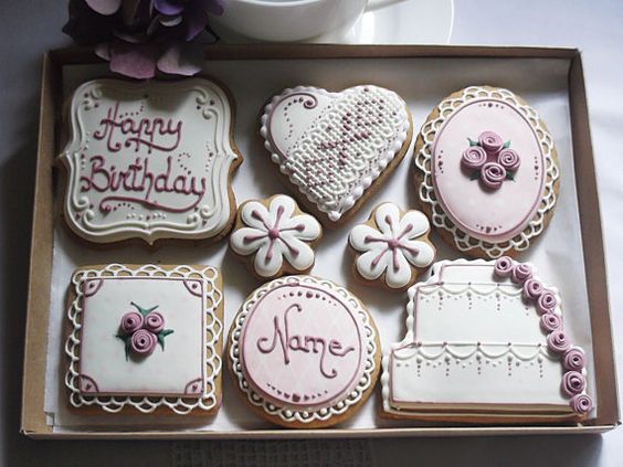 A box of decorated cookies and a cup of coffee surrounded by royal icing