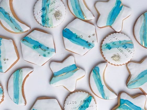 A table filled with a bunch of Quinceanera themed cookies decorated with turquoise royal icing