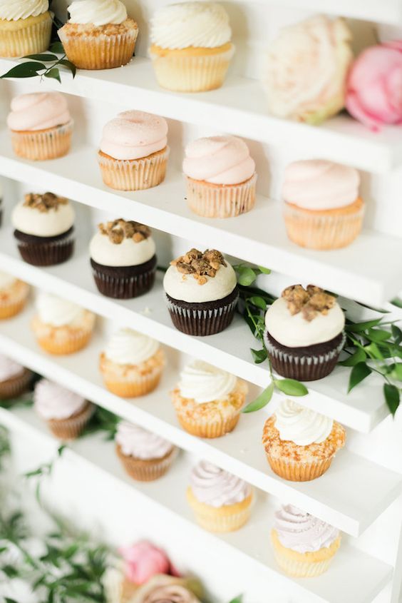 A display of Quinceanera themed cupcakes on a white shelf