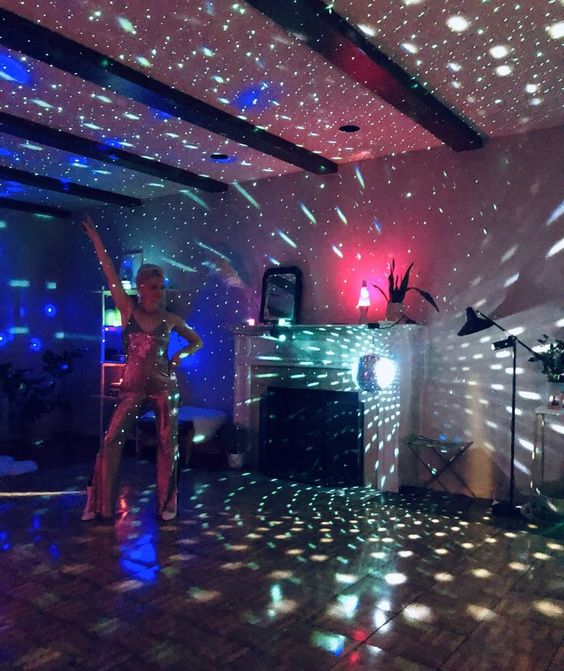 A woman standing in a room with a disco light, creating an atmosphere of euphoria at a Quinceanera disco party.