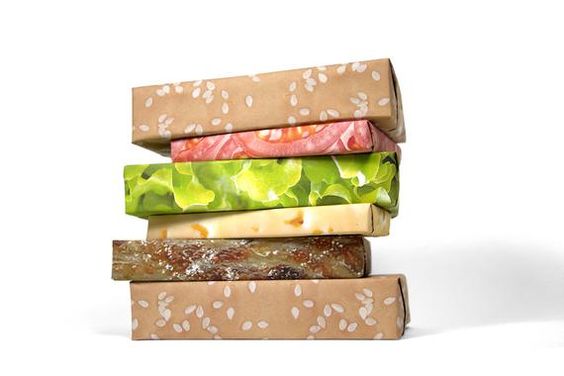 A stack of four sandwich burgers wrapped in hamburger-themed wrapping paper, perfect for a Quinceanera celebration.