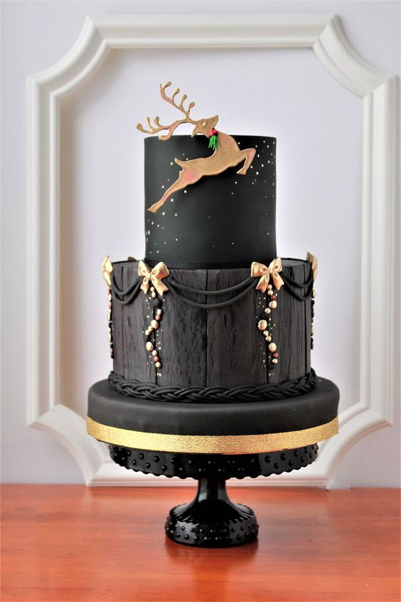An elegant Quinceanera cake with a black and gold design, featuring a deer on top.