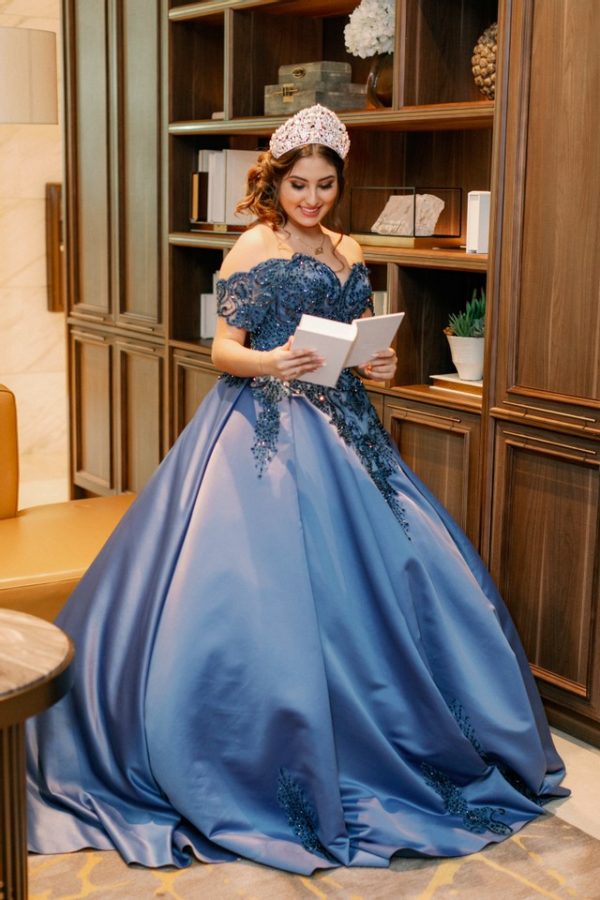 Quinceanera Gown, a woman in a blue ball gown holding a tablet