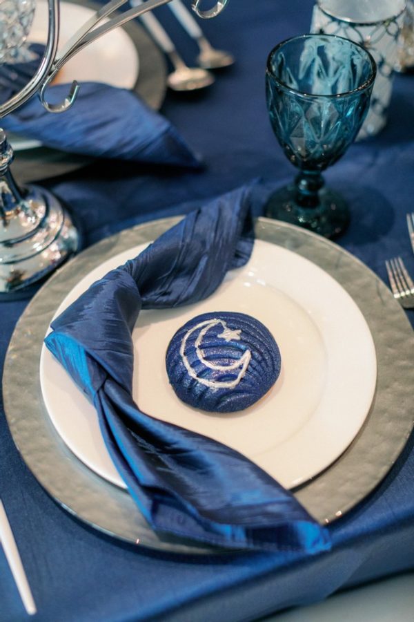 A Quinceanera birthday table setting featuring blue and white tableware, with a blue napkin.