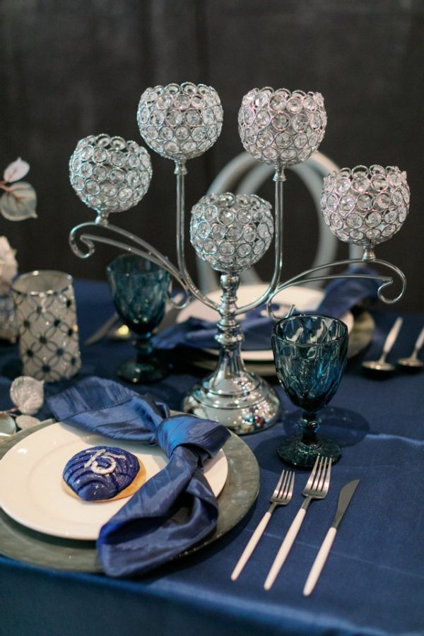 A Quinceanera flower dress displayed on a table with a blue table cloth and silverware