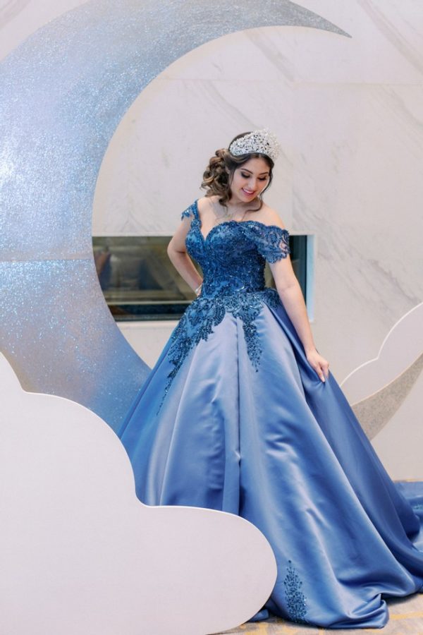 Quinceanera: A woman in a blue dress posing for a picture in a gown