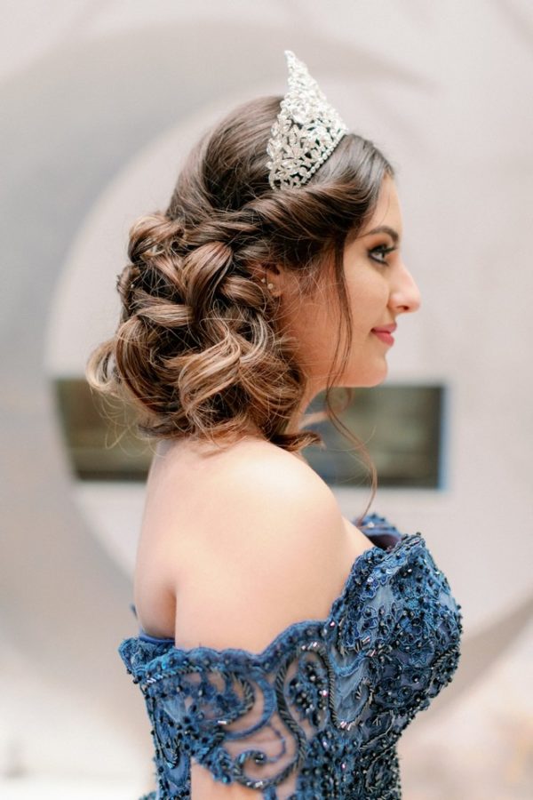 A woman in a blue dress wearing a headpiece and tia on her head