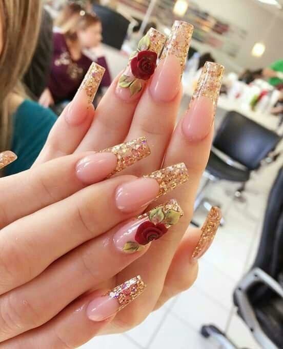 Quinceanera beauty and the beast acrylic nails. Nail art featuring a woman holding a manicure with gold and red flowers on it.