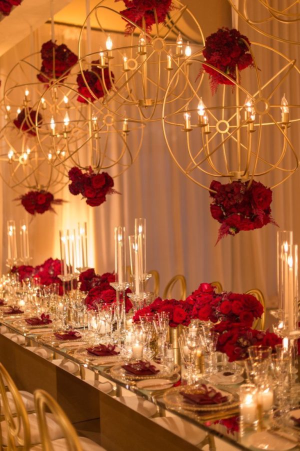 Glam red and gold Quinceanera, a long table with candles and flowers on it