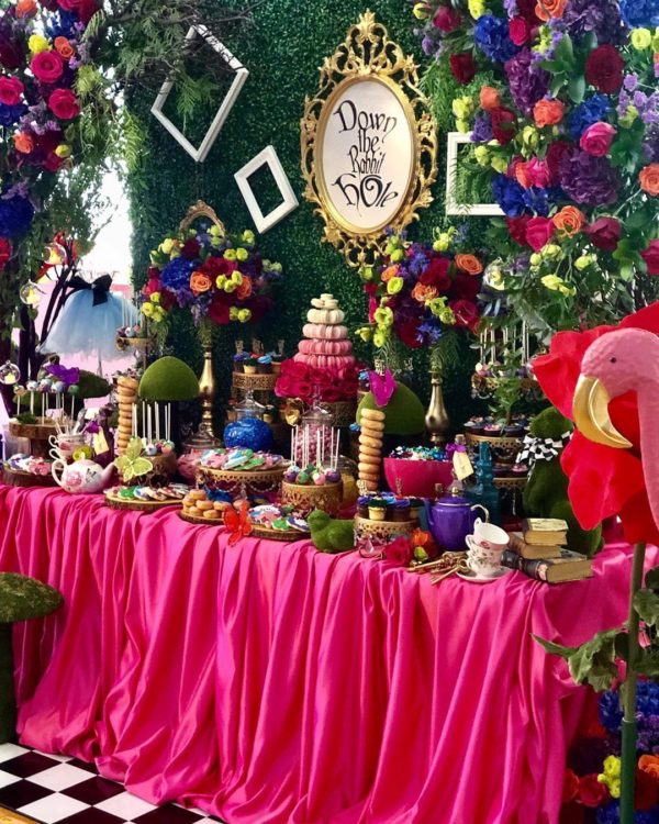 Quinceanera Alice in Wonderland centerpieces. A table topped with lots of food and decorations for a Quinceañera celebration.