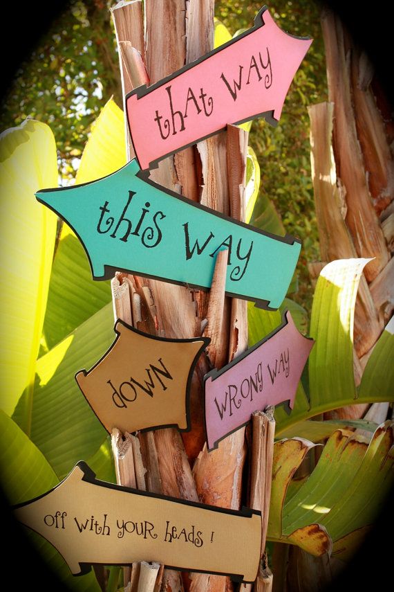 A Quinceanera themed image featuring Alice in Wonderland signs with the Hatter and a tree with a bunch of signs on it.