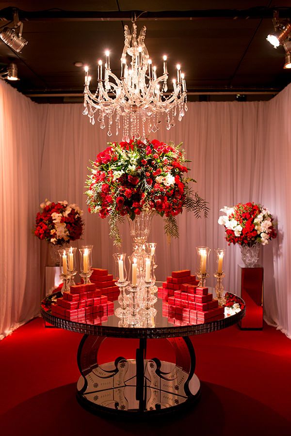 A beautiful Quinceanera decoration featuring red decorations, Quinceañera dresses, a table with a chandelier and flowers on it